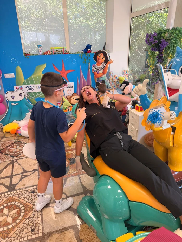 Un bambino gioca al dentista mentre Azzurra è seduta sulla poltrona